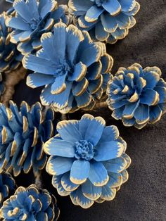 blue and gold flowers are arranged on a black surface with dark fabric in the background