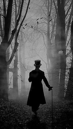 a man with a top hat and cane walking through the woods