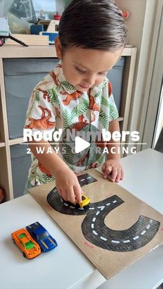 a young boy is playing with his cars in the cardboard box that he made for him