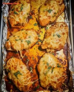 chicken parmesan in a baking pan with melted cheese and herbs on the top