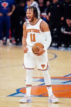 a man holding a basketball in his right hand and laughing while standing on a court