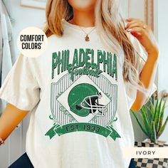 Show off your Philadelphia Eagles pride with this retro t-shirt, designed for women who love vintage style! Featuring an oversized 90's look, this trendy t-shirt is perfect for game day or casual wear. Made from high-quality Comfort Colors fabric, it's an ideal gift for her, a girlfriend, or anyone who loves a classic boho vibe. This retro-style t-shirt is perfect for women who want to support their team in a stylish and comfortable way. Whether it's a sorority gift or a cute game-day outfit, th Philadelphia Eagles Womens Shirts, Retro Oversized Tops For Game Day, Oversized Retro Top For Game Day, Oversized Vintage Green T-shirt, Green Oversized Vintage T-shirt, Oversized Green Retro T-shirt, Retro Oversized T-shirt For College, Philadelphia Eagles Shirts, Eagles Shirt