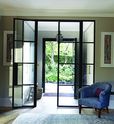 a blue chair sitting in the middle of a living room next to a doorway with glass doors