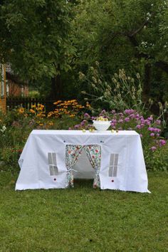 the table is set up outside in the yard for an outdoor meal or party with flowers and greenery around it