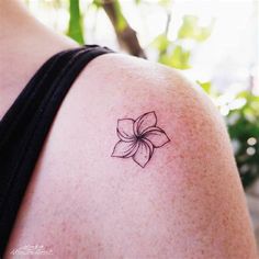 a woman with a tattoo on her shoulder has a flower in the middle of her arm