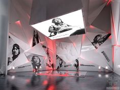 an art gallery with large white and red paintings on the walls, suspended by lights