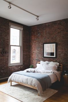 a bedroom with brick walls and a bed in the corner, along with a rug on the floor