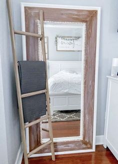 a ladder leaning against the wall in front of a mirror with a bed behind it