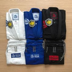 four different colored karate uniforms sitting on top of a wooden floor next to each other