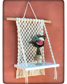 a macrame hanging on the wall with flowers in a vase next to it