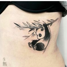 a panda bear tattoo on the side of a woman's lower back piece, with bamboo