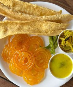 an assortment of food on a plate with sauces and breadsticks next to it