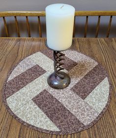 a candle sitting on top of a wooden table next to a white candle in a metal holder