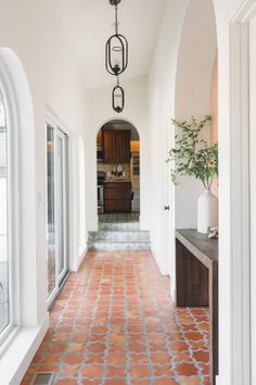 an archway leads to the kitchen and dining room in this home with red tile flooring