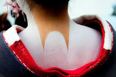 the back of a woman's neck with white paint on her face and chest