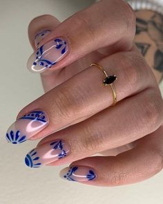 a woman's hand with blue and white designs on her nails, holding a gold ring