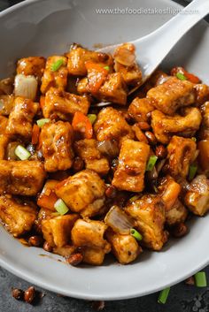 a white bowl filled with chicken and vegetables on top of a table next to chopsticks