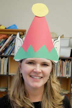 a woman wearing a paper hat with an unicorn on it's head in front of a bookshelf