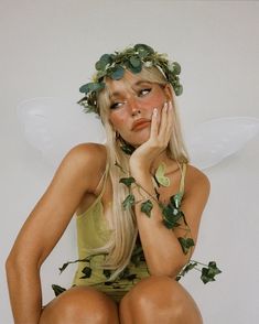 a woman dressed as tinkerbell sitting on top of a stool with her hands to her face