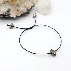 This minimal Pyrite bracelet is made with black waxed cotton cord and sliding knot that allows you to slide it over your hand and tighten it to your desired fit ◇ Meaning Pyrite is a powerful protection stone. It stimulates the intellect and enhances memory, helping to recall relevant information. Pyrite assists one in seeing behind facades, promoting an understanding of that which lies beneath words and actions. ◇ Suggestions Everyone responds differently to crystals. What works for one may not Everyday Braided Bracelet With Sliding Knot, Adjustable Waxed Cord Jewelry For Everyday, Minimalist Adjustable Friendship Bracelets, Adjustable Spiritual Friendship Bracelet With Sliding Knot, Adjustable Spiritual Friendship Bracelets With Sliding Knot, Spiritual Friendship Bracelet With Sliding Knot For Everyday, Spiritual Friendship Bracelets With Sliding Knot For Everyday, Adjustable Minimalist Friendship Bracelets With Waxed Cord, Minimalist Adjustable Waxed Cord Bracelets