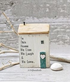 a small wooden house sitting on top of a table next to some rocks and driftwood