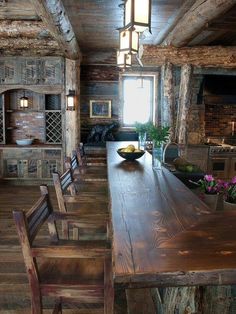 an old log cabin kitchen with wooden tables and chairs in the center, along with wood flooring