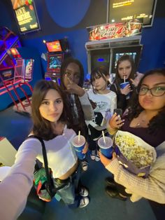 four girls are eating popcorn and drinking sodas