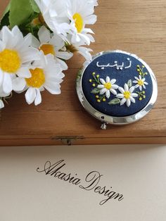 a blue case with daisies on it next to a paper and some white flowers