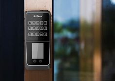 an electronic door lock on the outside of a house with glass doors and windows in the background