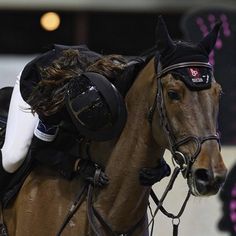 a person riding on the back of a brown horse wearing headphones and harnesses