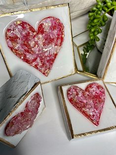 three framed pictures with pink and gold designs on them, one is shaped like a heart