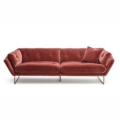 a red velvet couch with two pillows on it's back and one arm extended