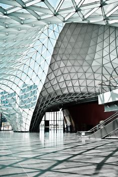 the interior of an airport with glass walls and ceiling tiles on the floor, as well as stairs leading up to it