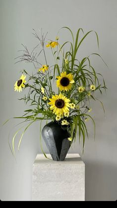 a vase filled with yellow flowers sitting on top of a white block