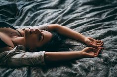 a young woman laying on top of a bed