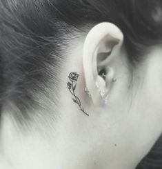 a woman's behind the ear tattoo with a single flower on her left side