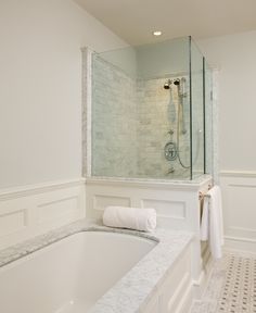 a white bathroom with marble counter tops and bathtub