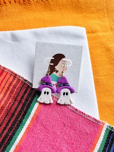 the earrings are purple and white with ghost faces on them, along with an orange sweater