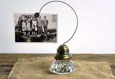 an old fashioned photo is hanging on the wall next to a small glass bottle with a rope