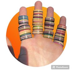 a person's hand with five different colored rings on their fingers and the ring is made out of strips of wood