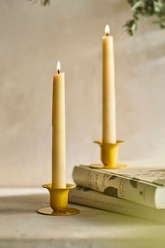 two candles sitting on top of a table next to a book