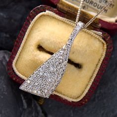 This graceful diamond ribbon pendant features seventy-seven (77) round brilliant cut diamonds that are pavé set. The pendant measures 34.5mm long, by 12.0mm wide and 5.5mm thick. It hangs on an 18 inch long, 1.0mm wide wheat chain that is finished with a lobster claw clasp. Formal Art Deco Diamond Necklace With Accents, Diamond White Necklace With Diamond Accents For Evening, Exquisite Diamond Necklace For Evening, Art Deco Diamond Necklace With Accents, Art Deco Necklace With Diamond Accents, Art Deco Diamond Pendant Necklace With Accents, Dazzling Diamond Necklace For Evening, Art Deco Diamond Necklace In Diamond White, Evening Diamond Necklace With Single Cut Diamonds