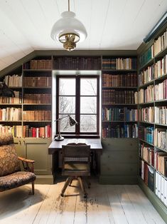 a room with many bookshelves and a desk in the corner, along with a chair