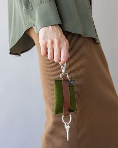 a woman holding onto a key chain with a green case on it's side