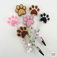 four different colored dog paw pens with black and white polka dots on the top one has pink, brown, and orange paws