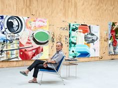 a man sitting on a chair in front of paintings