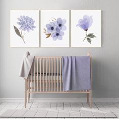 three blue flowers are hanging on the wall next to a crib with a blanket