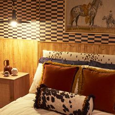 a bed with two pillows on top of it next to a night stand and lamp