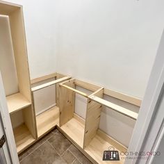 an empty room with wooden shelves in the corner and tile flooring on the other side