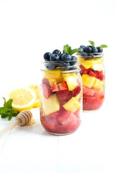 two mason jars filled with fresh fruit and honey